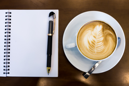 Coffee cup and notebook on table backgroundの写真素材