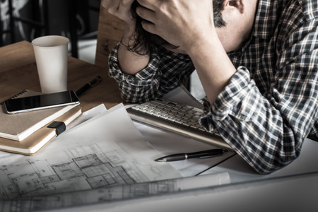 Businessman serious examining blueprints with dark retro style.の写真素材