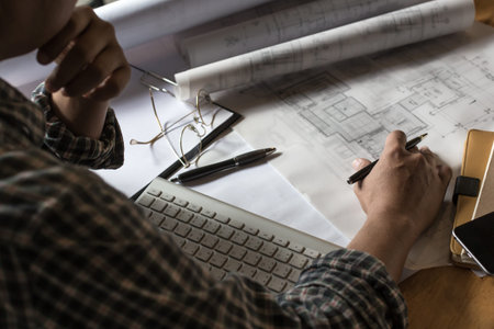 Creative architect projecting on the big drawings in the dark loft office or cafe with dark and...