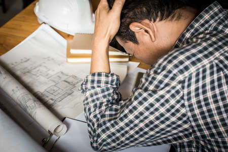 Businessman serious examining blueprints with dark retro style.の写真素材