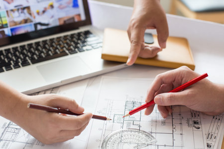 Architects discussing at the table with blueprint - Closeup on hands and project print.