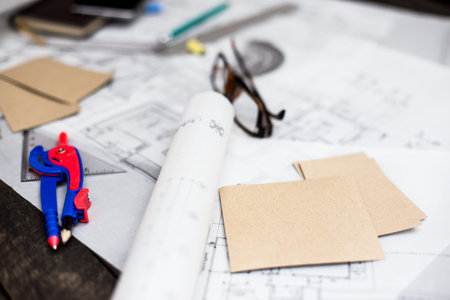 Construction planning drawings on the table with pencils, ruler and glasses on the table, retro...