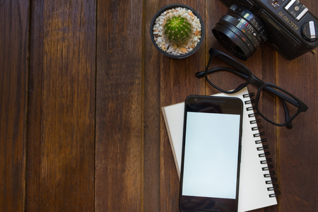 Close up of mart phone empty white screen and material office desktop on wooden desk top viewの写真素材