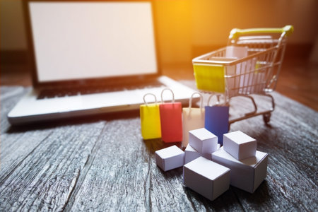 laptop blank screen and hopping cart full of gifts with copyspace, online shopping concept.