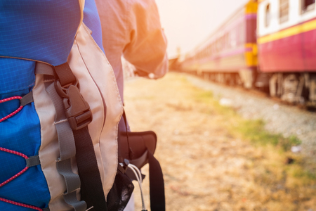 Young hipster man with a backpack ready to embark on a journey by train, Trendy guy standing looking away.の写真素材