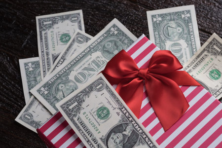 Banknote of dollar in red bow decorated gift box