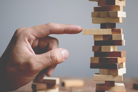Planning, risk and strategy in business, businessman and engineer gambling placing wooden block on a tower.の写真素材