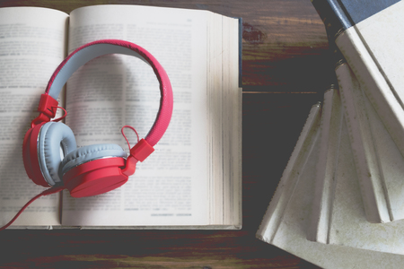 Concept of audiobook. Books on the table with headphones put on them.の写真素材