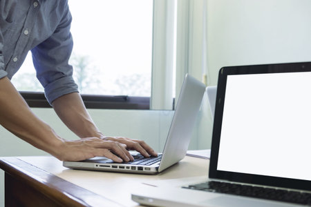 Young adult business man typing using laptop in office.