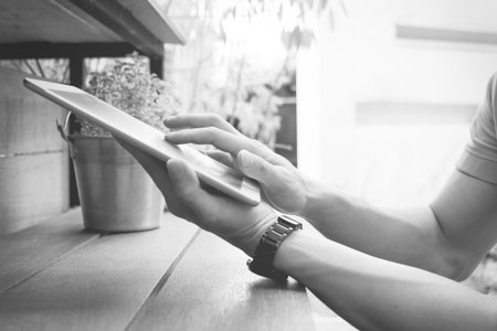 Man hands touching lablet with tree background.