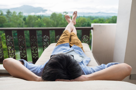 Young man relax on bed and enjoying mountain view.の写真素材