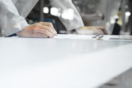 man writing on notebook with digital tablet on wooden table, selective focus and vintage tone.