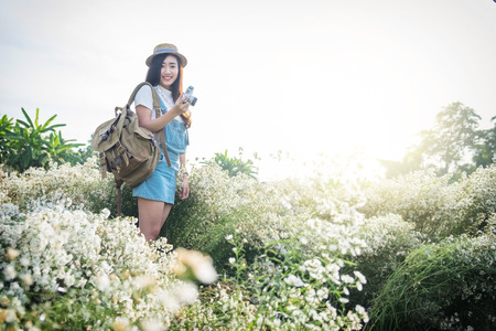 Asian hipster cute teen girl with camera in white flower garden, with vintage tone nature concept.の写真素材