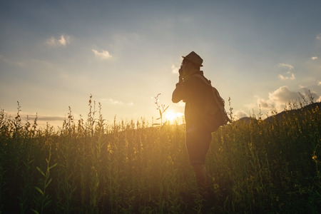 Silhouette of a young who like to travel and photographer, taking pictures of the beautiful moments during the sunset ,sunriseの写真素材