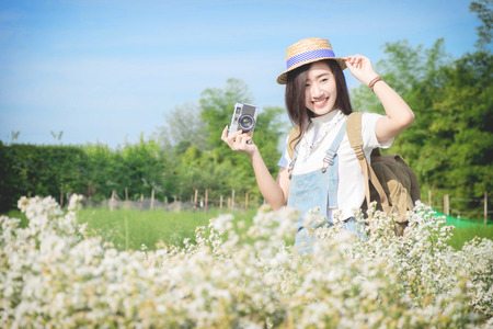 Asian hipster cute teen girl with camera in white flower garden, with vintage tone nature concept.の写真素材