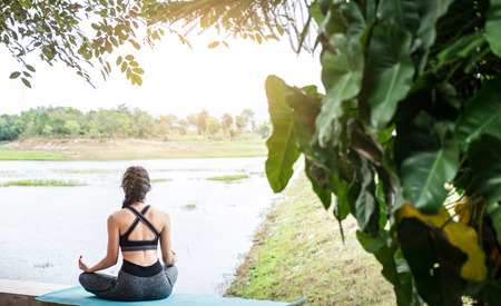 Rear view close up of woman perform meditating yoga on the nature background in the morningの写真素材