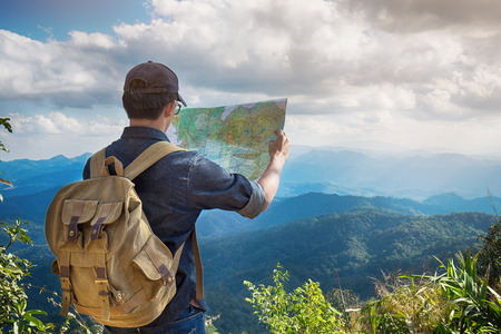 Young Man Traveler with map backpack relaxing outdoor with rocky mountains on background Summer vacations and Lifestyle hiking concept.の写真素材