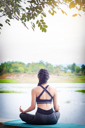 Rear view close up of woman perform meditating yoga on the nature background in the morningの写真素材