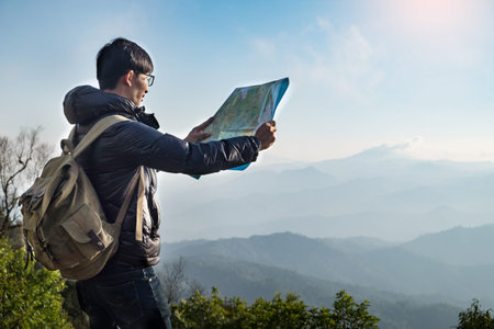 Young Man Traveler with map backpack relaxing outdoor with rocky mountains on background Summer...