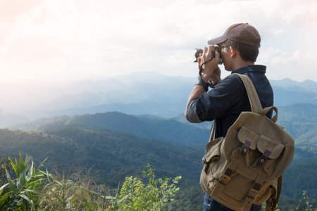Young professional travrler man with camera shooting outdoor, fantastic mountain landscape.