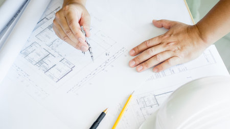 Close-up Of Person's Hand Drawing Plan On Blue Print with architect equipment