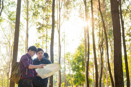 Hiking couple looking at map hiking in forest. Young interracial hiker couple, Asian man
