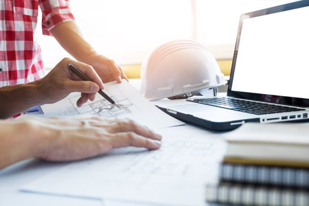 Architects engineer discussing at the table with blueprint - Closeup on hands and project print.