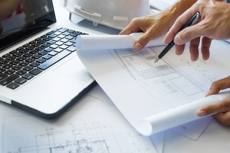 Architects engineer discussing at the table with blueprint - Closeup on hands and project print.の写真素材