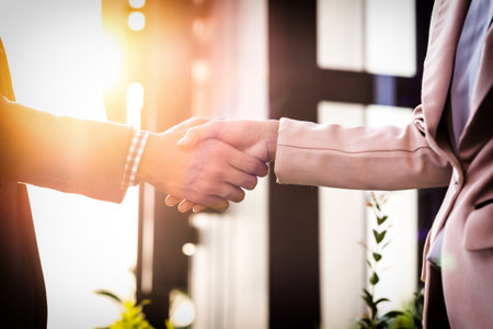 Closeup friendly meeting handshake between business woman and  businessman with sunlight.の写真素材
