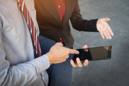 Business man and woman discuss about the financial plan on digital tablet outdoor.の写真素材
