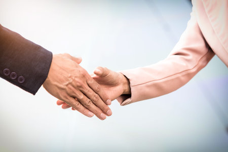 Closeup friendly meeting handshake between business woman and  businessman with sunlight.