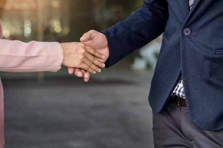 Closeup friendly meeting handshake between business woman and  businessman with sunlight.の写真素材