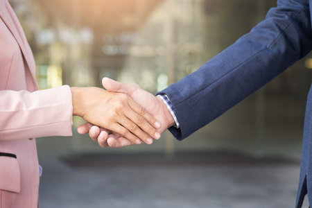 Closeup friendly meeting handshake between business woman and  businessman with sunlight.