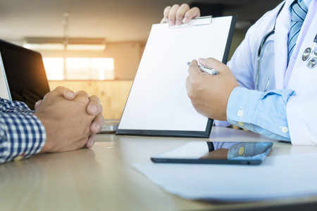 patient listening intently to a male doctor explaining patient symptoms or asking a question as they...