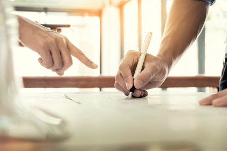 Architects engineer discussing at the table with blueprint - Closeup on hands and project print.