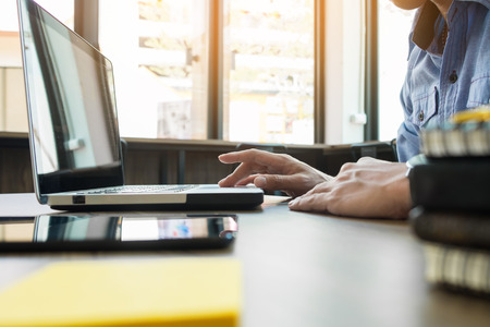 Attractive  man in casual business sitting at a table working on his laptop computer at home office in front of a window.の写真素材