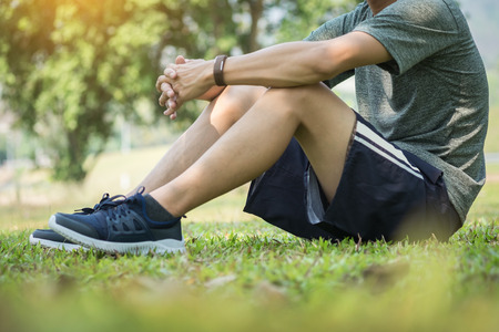 Healthy male athlete is resting on grass and bottle of water.の写真素材