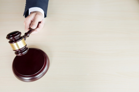 hand of Judge's holding wooden hammer knocking a gavel against wooden background.の写真素材