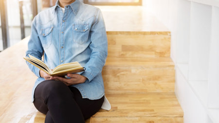 Thoughtful female student sitting Serious reading a book in a library floor, Education conceptの写真素材