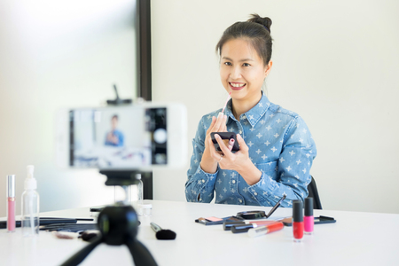 woman present beauty cosmetic product and broadcast live video to social network by internet at home, beauty blogger conceptの写真素材
