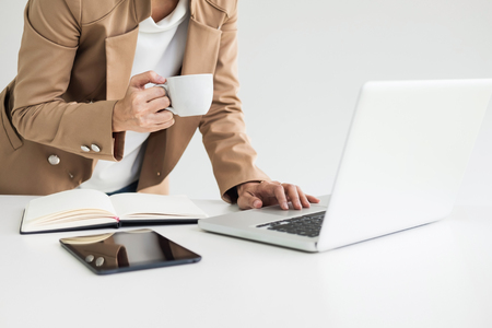 Attractive women in casual business sitting at a table working on her laptop computer at home office in front of a windowの写真素材
