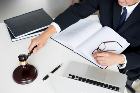 Male Judge lawyer In A Courtroom Striking The Gavel on sounding block.の写真素材