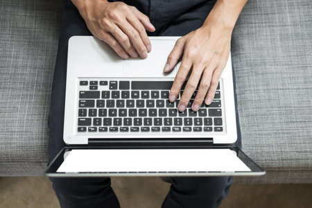 Man uses laptop on sofa in his home. High angle view,  Work at home concept.