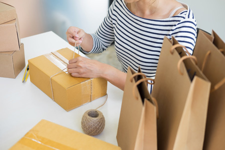 Business owner woman working online shopping prepare product packaging process at her home, young entrepreneur conceptの写真素材
