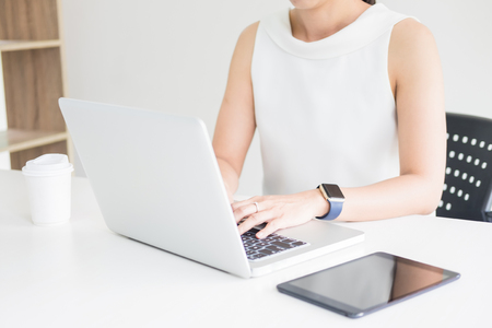 Attractive women in casual business sitting at a table working on her laptop computer at home office in front of a windowの写真素材