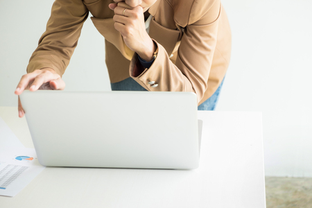 Attractive women in casual business sitting at a table working on her laptop computer at home office in front of a windowの写真素材