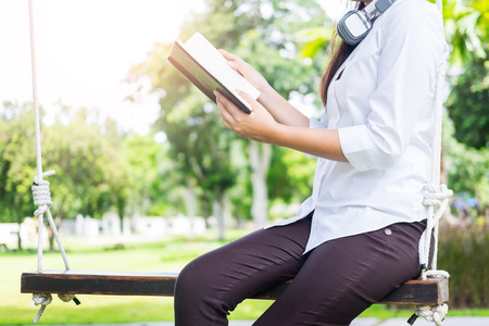 Pretty relaxed young beautiful woman reading a book in the garden  lawn with sun shiningの写真素材