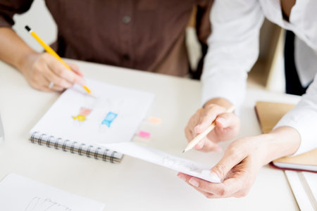 two young men working as fashion designers and drawing sketches and gets fabric advice at a custom tailorの写真素材