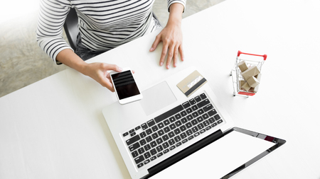 Closeup of happy young woman holding credit card inputting card information while and using smart phone at home. Online shopping conceptの写真素材