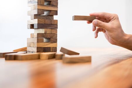 Business man placing wooden block on a tower concept of risk control planning risk and strategy の写真素材